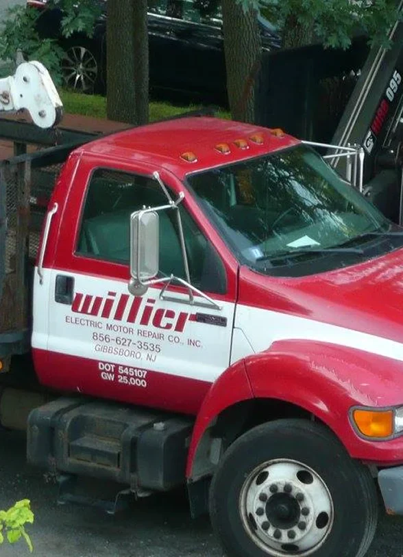 Red truck with 'Willier Electric Motor Repair' logo; phone number and location details visible. Parked among trees