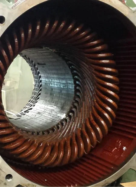 Close-up of an electric motor's rotor, showcasing copper windings inside a circular casing with a smooth metallic surface